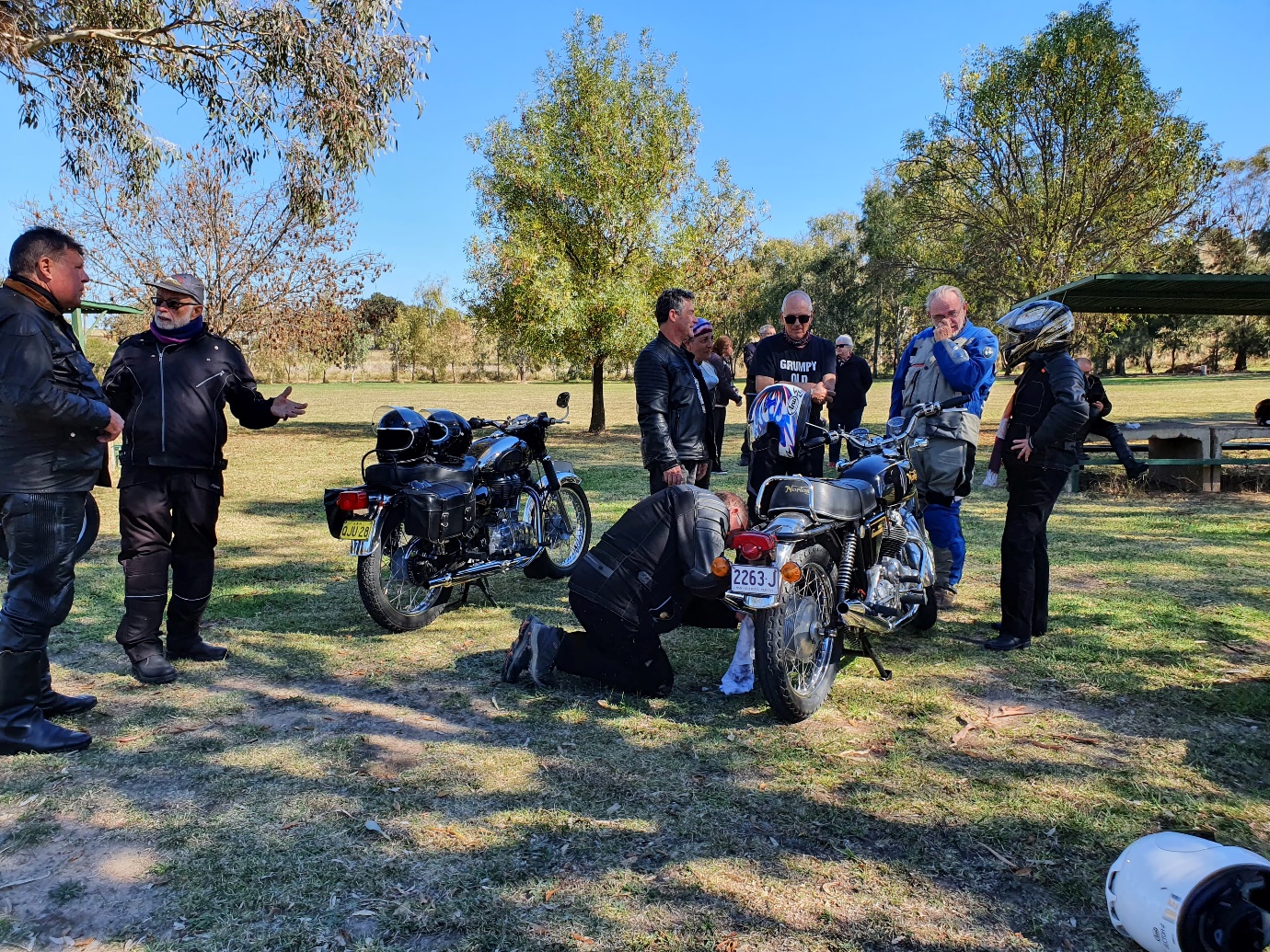 A group of people stand around motorcycles

Description automatically generated with medium confidence