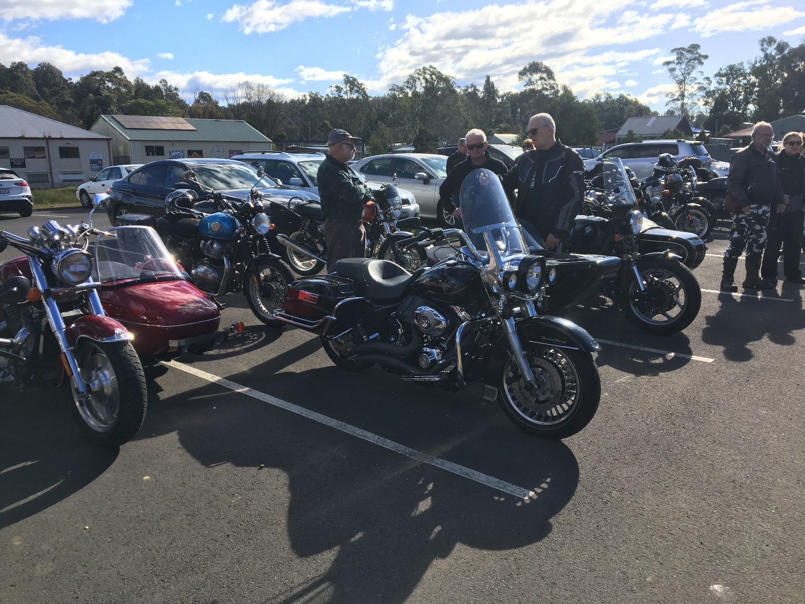 A group of men standing next to motorcycles Description automatically generated with low confidence
