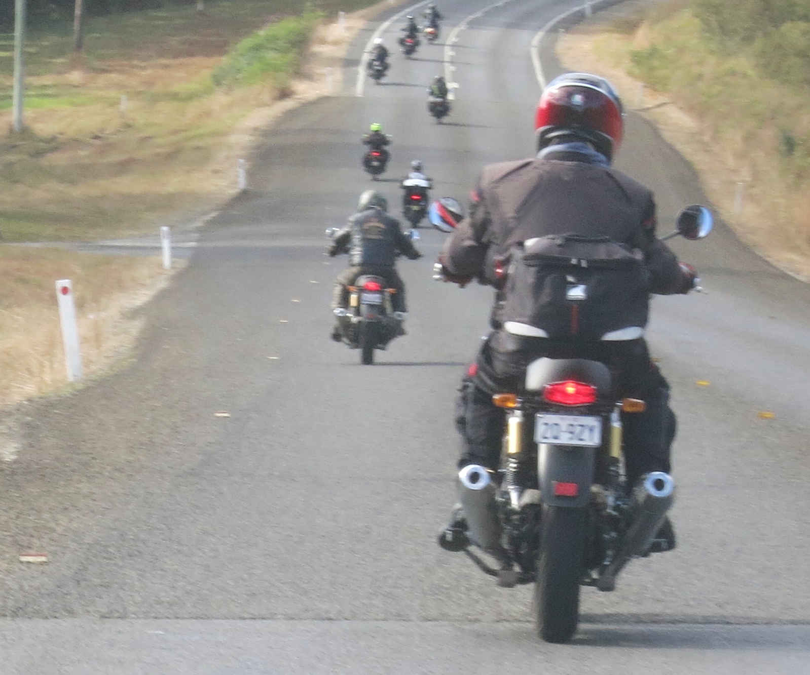 A group of people riding motorcycles down a road Description automatically generated with medium confidence