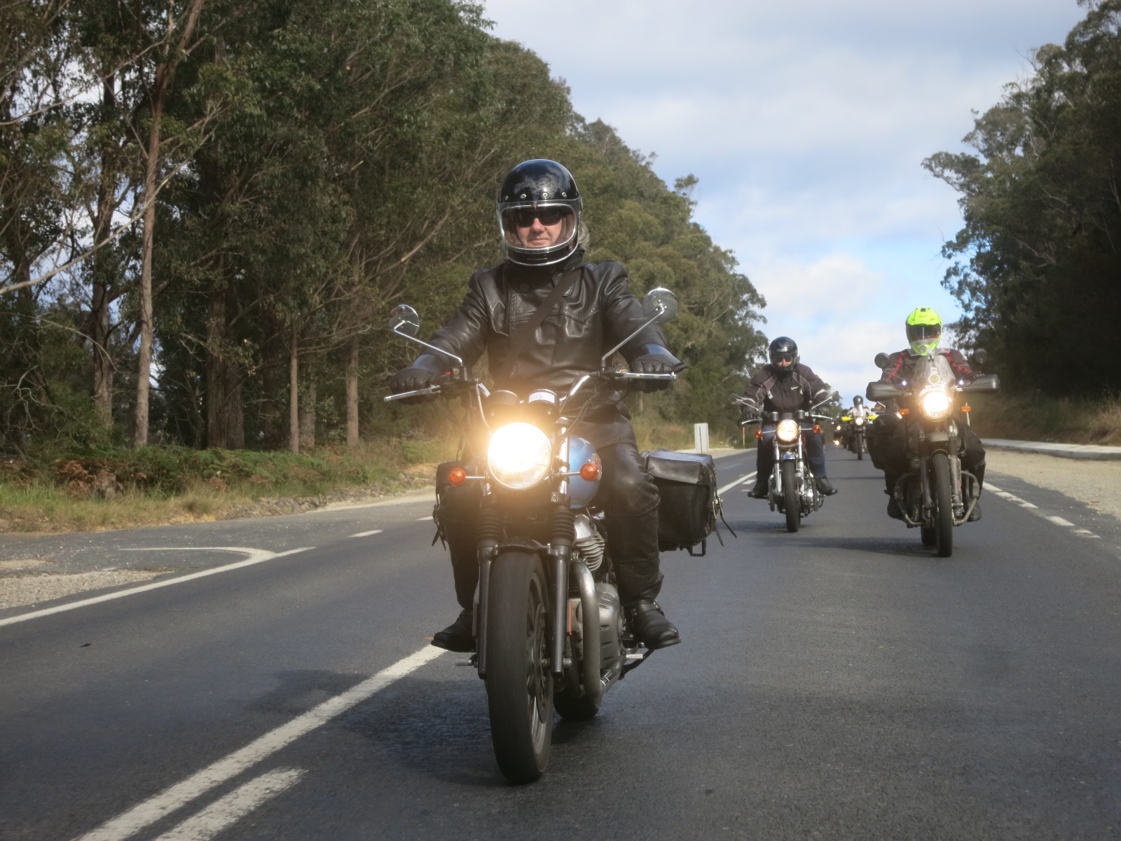 A group of people riding motorcycles down a road Description automatically generated with low confidence