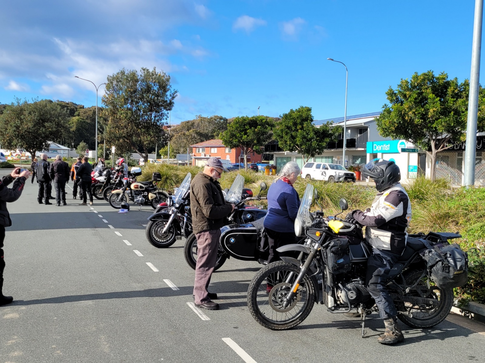 A group of people stand around motorcycles Description automatically generated with low confidence