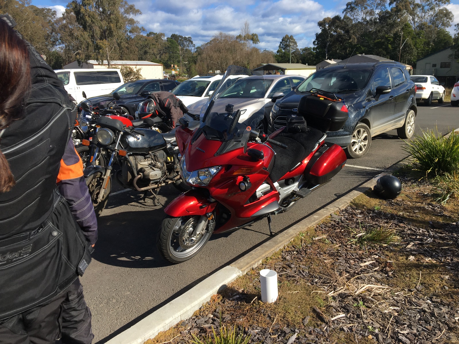 A red motorcycle parked on the side of a road Description automatically generated with low confidence