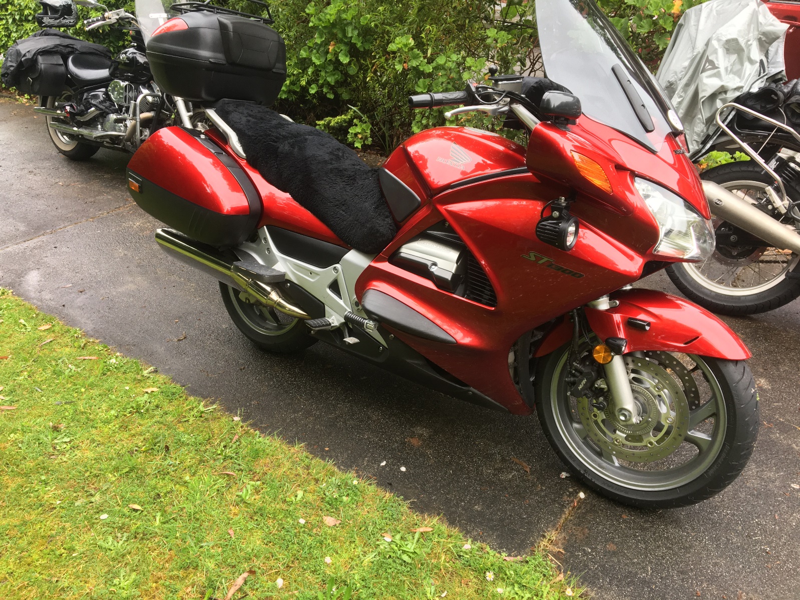 A red motorcycle parked on the side of a road Description automatically generated with medium confidence